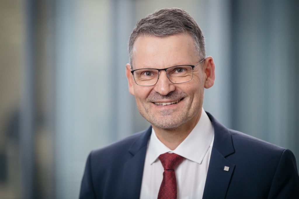 Seitenansicht eines gut gekleideten Mannes mit Brille, der professionell in einem modernen Büro arbeitet.