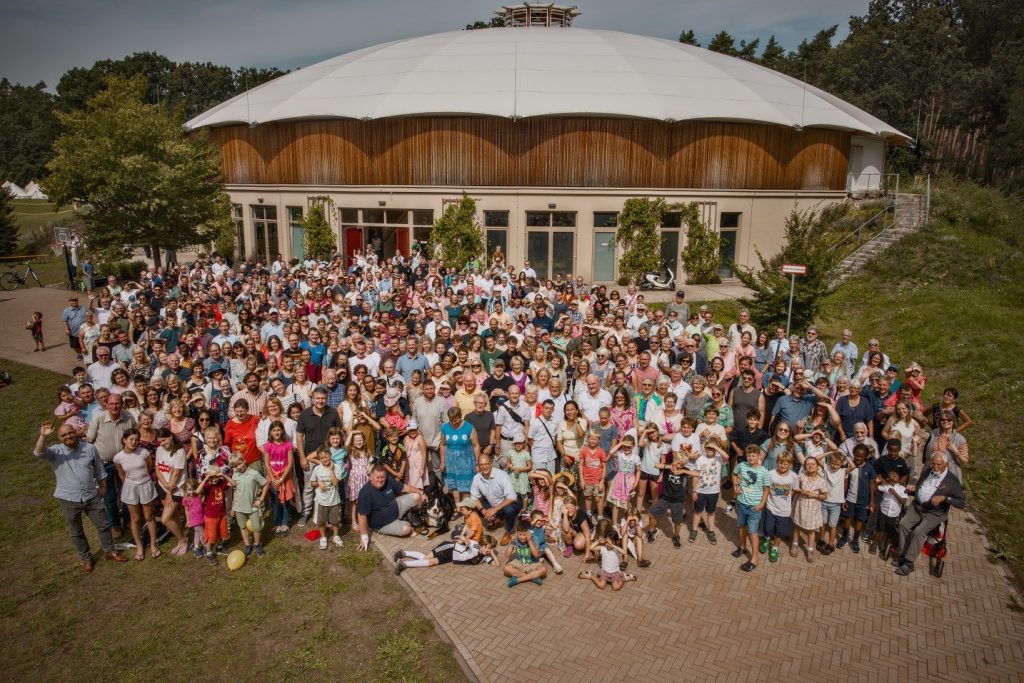 Große Gemeinschaftsgruppe vor dem Veranstaltungsgebäude bei Advent-Verlag, umgeben von Natur, für kirchliche Events, Workshops und Familienfeiern, in einer ländlichen Umgebung in Deutschland.