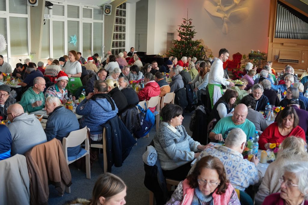 Fröhliches Weihnachtsessen mit einer großen Gemeinschaft in festlicher Stimmung, geschmückt mit Weihnachtsdeko und Kerzen, in einem festlich dekorierten Raum.